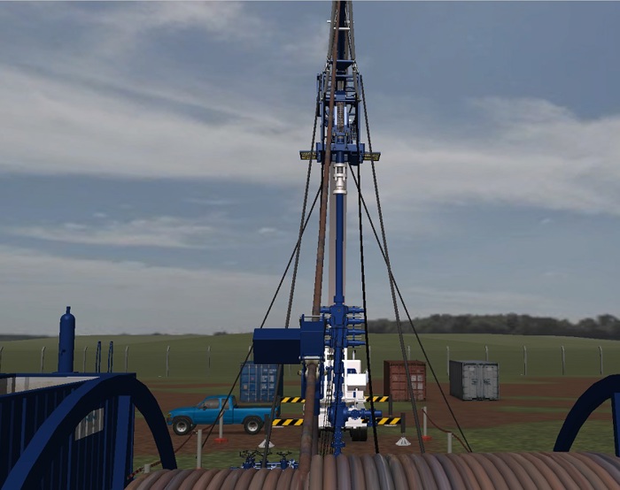 A drilling rig is set up in a field with machinery, a truck, and storage containers nearby under a cloudy sky.