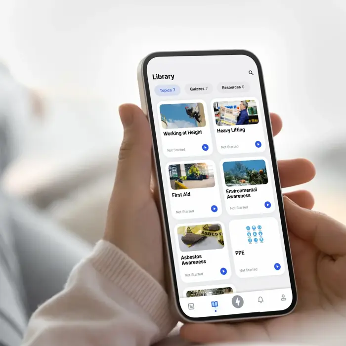 Person using a smartphone app to browse a library of courses including "Working at Height," "First Aid," "Asbestos Awareness," among others, with options categorized under various topics and sectors.