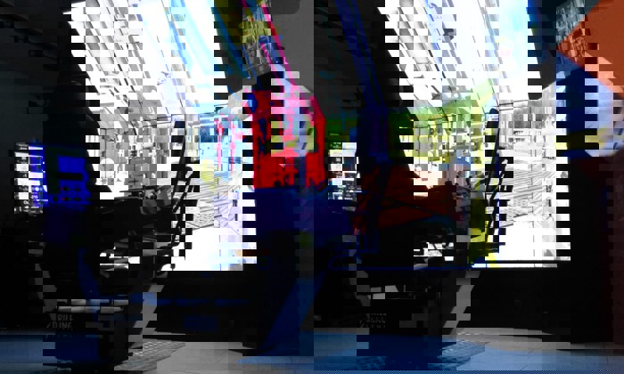 A simulator setup features a large screen displaying equipment, a control chair, and various monitors.