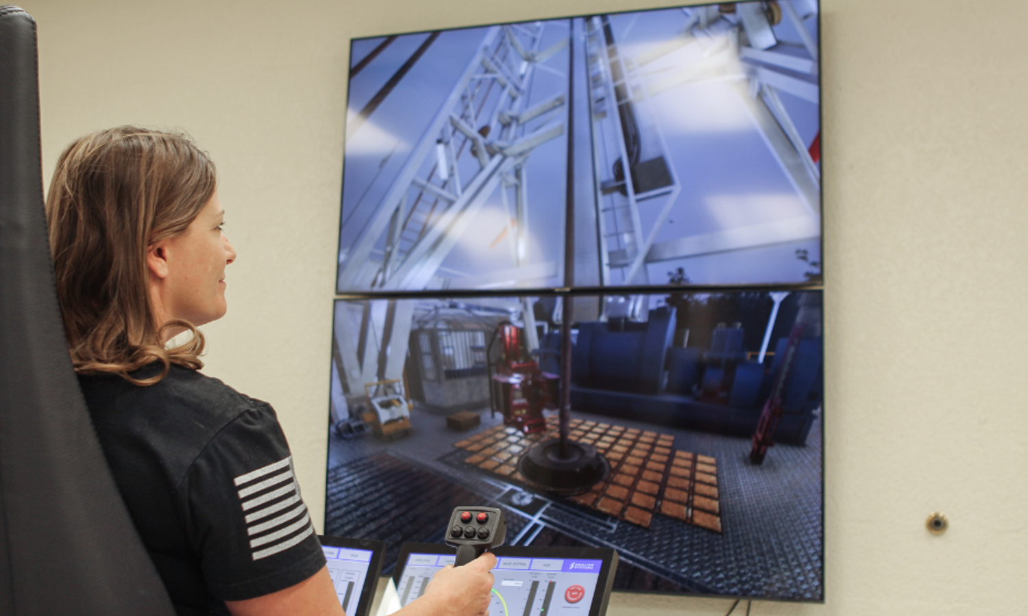 A person operates a control system with screens displaying drilling operations.
